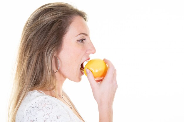 Profiel zijportret van vrouw van het schoonheids de vrolijke jonge blonde die rode gele appel eten