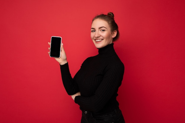 Profielfoto aan de zijkant van een aantrekkelijke, positieve jonge brunette vrouw die een zwarte trui draagt ??