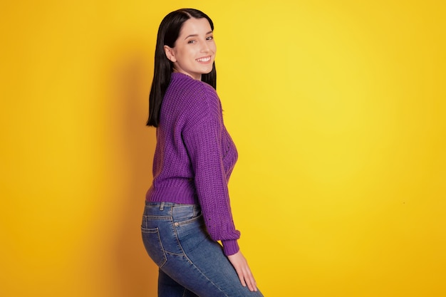 Profielfoto aan de zijkant van een jonge, aantrekkelijke vrouw, een gelukkige positieve glimlach, zelfverzekerd, draag een casual outfit geïsoleerd over een gele kleurachtergrond