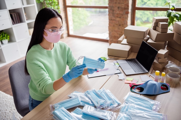 Profielfoto van aziatische dame familiebedrijf orde gezichtsgriep medisch masker verzenden voorbereiden levering anti-virale veiligheid plaats ademhalingstoestellen in ritszak blijf thuiskantoor binnenshuis