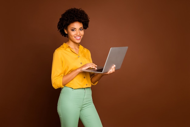 Profielfoto van mooie donkere huid zakelijke dame bedrijf notitieboekje zoeken bedrijfsinformatie schrijven e-mail dragen geel shirt groene broek geïsoleerde bruine kleur