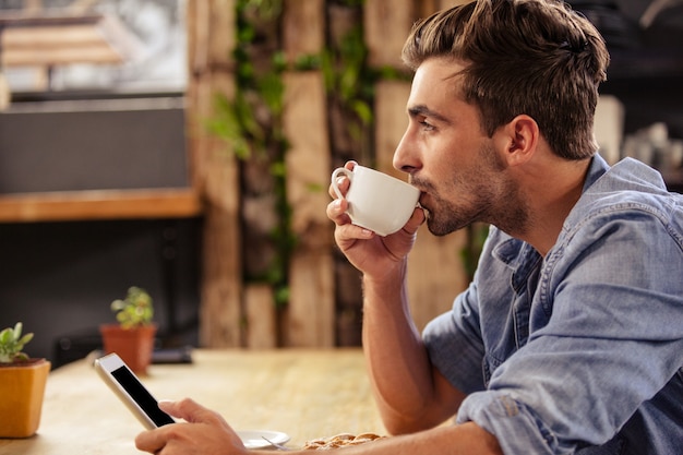 Profielmening van de hipstermens die tablet gebruiken bij koffie