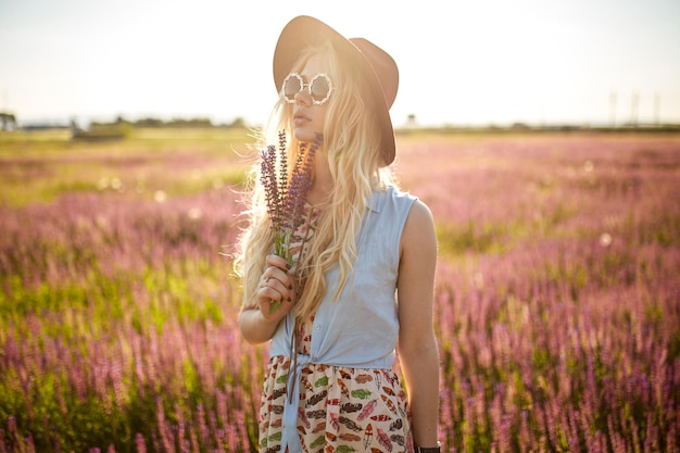 Profielportret van hipster prachtige vrouw die in het veld loopt en naar het mooie natuurconcept aan de zijkant kijkt