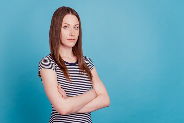 Profielportret van succesvolle zelfverzekerde dame gekruiste armen kijken camera op blauwe achtergrond