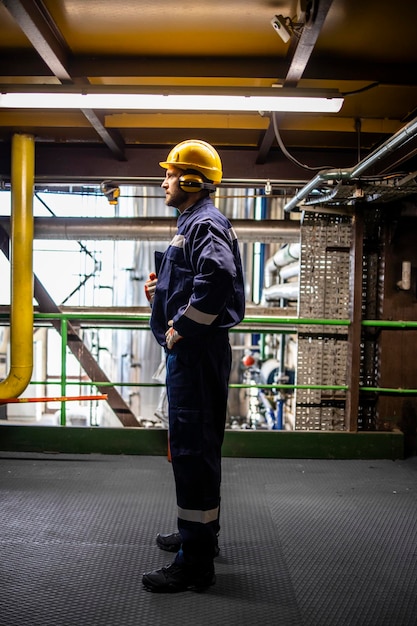 Profielweergave van een industriële werknemer in veiligheidsuitrusting die in een olie- en gasraffinaderij staat