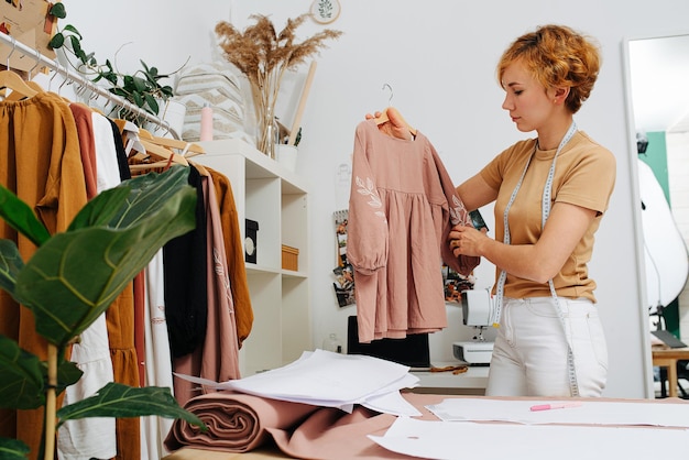 Profielweergave van een naaister die een chique overhemd op een hanger houdt