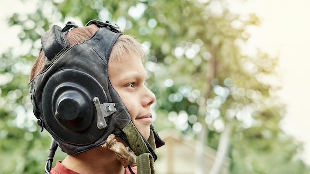 Profielweergave van een positieve tiener met een vintage lederen pilotenhelm die in het groene park staat