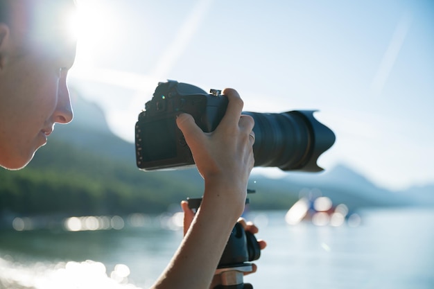 Profielweergave van vrouwelijke fotograaf die foto's maakt van een prachtige ochtendzee die gloeit in de opkomende zon