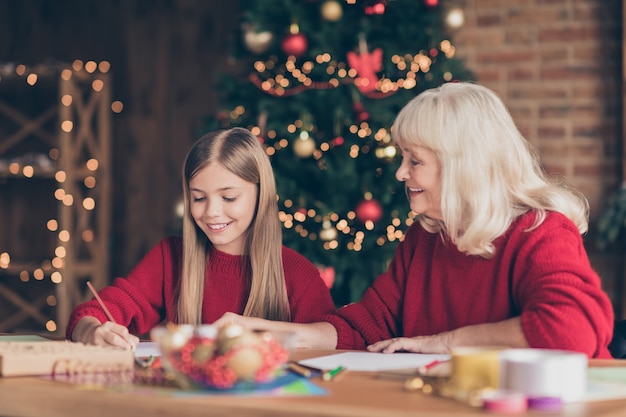 Profielzijde portret van oma kleinkind schrijven brief aan de kerstman in ingericht huis