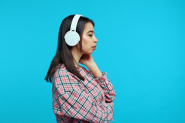 Profile of cute girl wears white headphones listens music with closed eyes