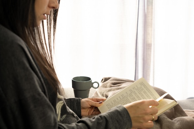 집에서 책을 읽는 동안 앉아 있는 여자의 프로필