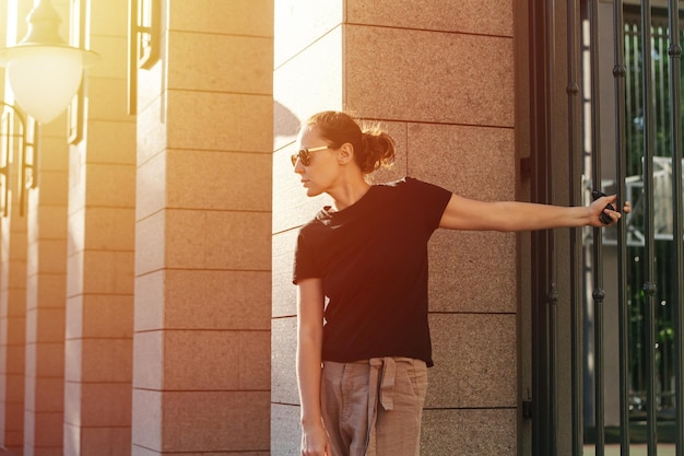 Profile image of a young woman in sunglasses holding a fence rail on a street