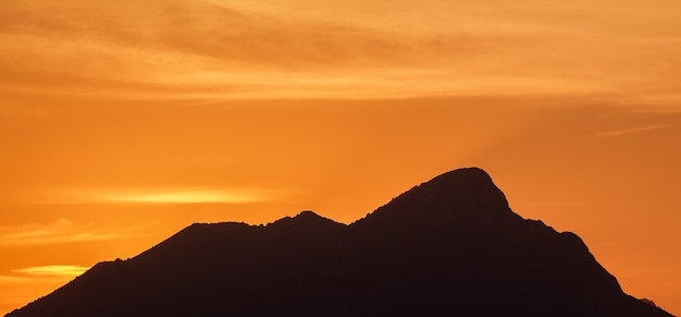 the profile of mount pizzocolo with an orange sunset in the background