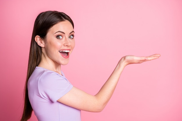 Profile photo of attractive funny excited lady hold open arm palm showing new product sale discount shopping low price wear casual purple t-shirt isolated pink pastel color background