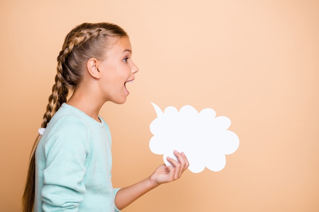 Photo profile photo of beautiful excited little lady hold empty paper cloud screaming loudly expressing ideas thoughts wear blue pullover isolated beige pastel color wall