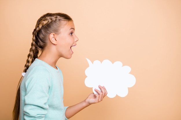 Foto del profilo della bella piccola signora eccitata tenere vuoto nuvola di carta urlando ad alta voce esprimendo idee pensieri indossare pullover blu isolato beige pastello parete di colore