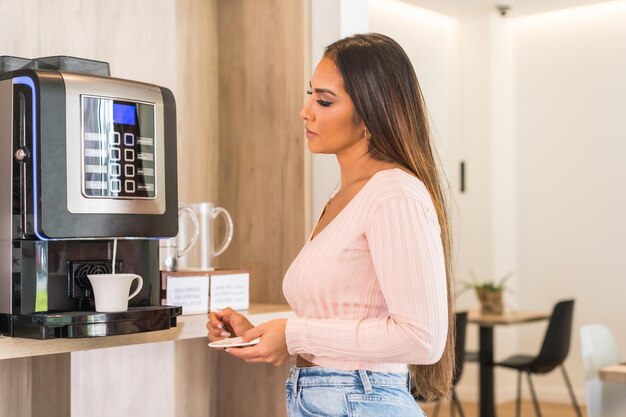 Photo profile photo of a casual business woman using a coffee machine in a breakfast buffet