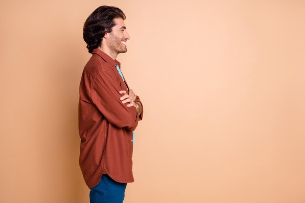 Profile photo of confident positive man folded arms look empty space wear brown t-shirt isolated beige color background