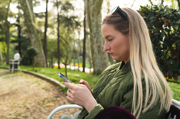 Foto foto del profilo della donna che utilizza il cellulare nel parco