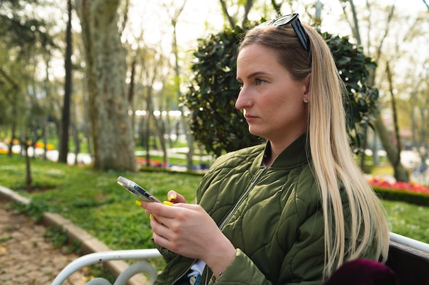 Foto del profilo della donna che utilizza il cellulare nel parco