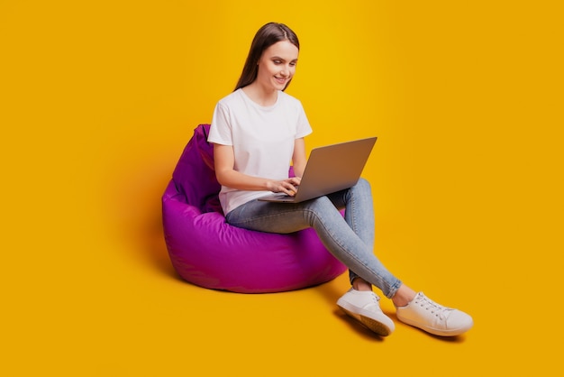 Profile photo of lady sit beanbag work netbook wear white t-shirt posing on yellow background