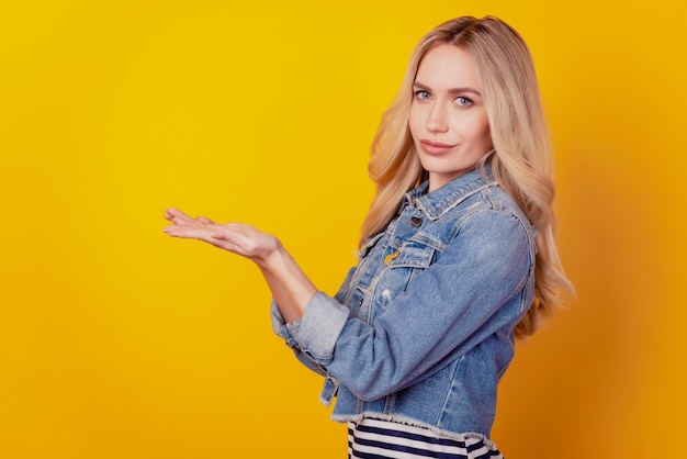 Profile portrait of adviser lady palm hold empty space look camera on yellow background