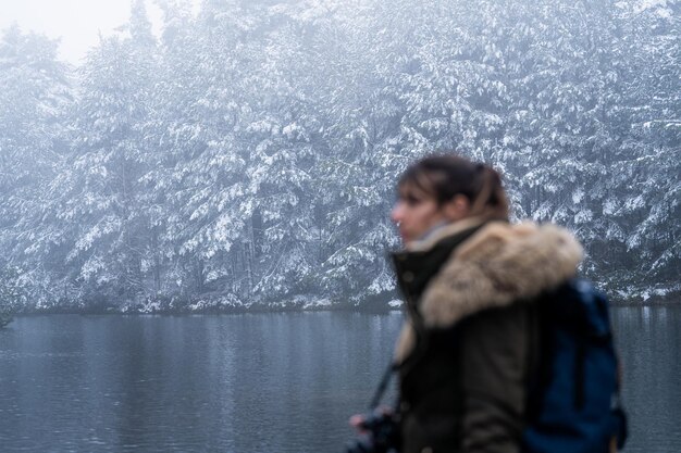 Photo profile portrait of blurry young woman gazing at snowy pine forest lake holding camera