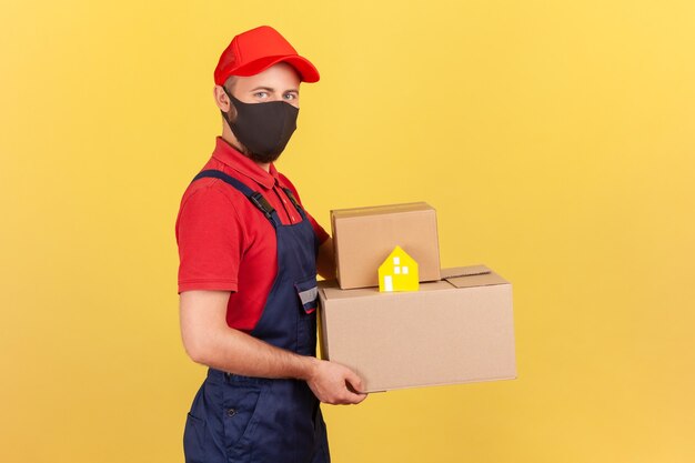 Profile portrait delivery man on face holding cardboard boxes and paper house