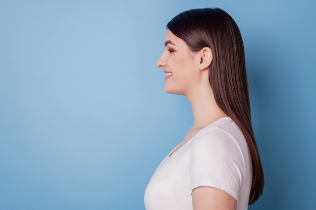 Profile portrait of positive cheerful cute lovely lady look empty space toothy smile on blue background