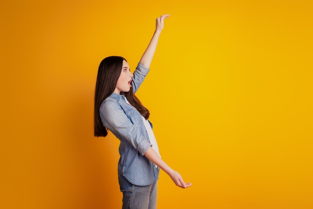 Profile portrait of woman isolated yellow background holding copyspace crazy face