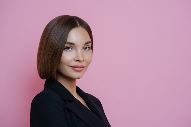 Profile shot of dark haired woman dressed in black suit, has natural makeup