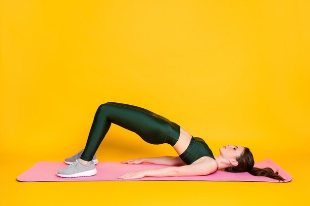 Profile side full body view of nice attractive slender girl trainer lying on mat doing exercise isol
