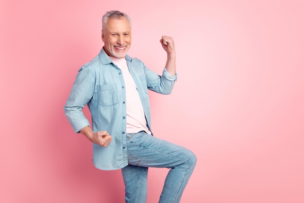 Profile side photo of mature man rejoice victory fists hands goal fan hooray isolated over pink color background.