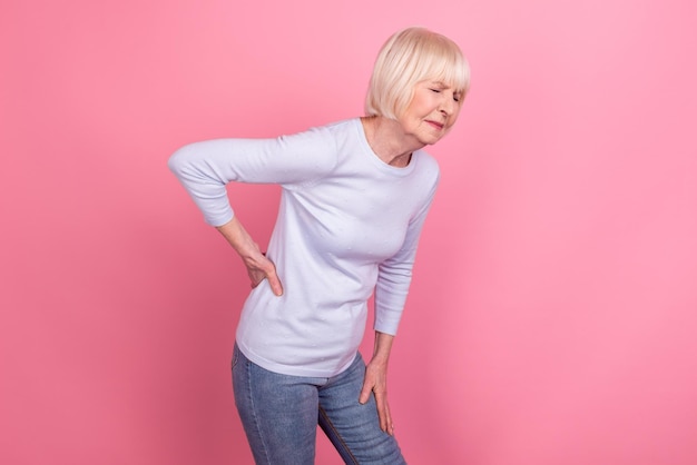 Profile side photo of mature woman hand on spine unwell sick sore medicine isolated over pink color background