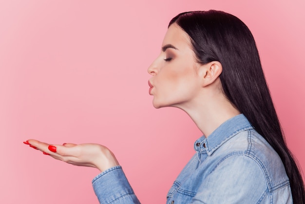 Profile side photo of pretty attractive girl pouted lips sending air kisses isolated bright pink color background