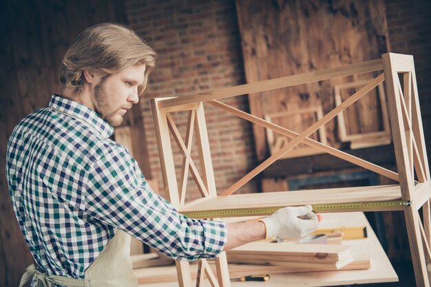 Profile side view of bearded craftsman posing in his woodshop