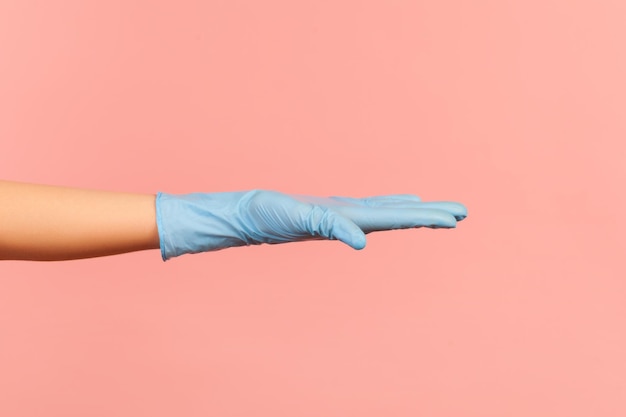 Profile side view closeup of human hand in blue surgical gloves showing hand