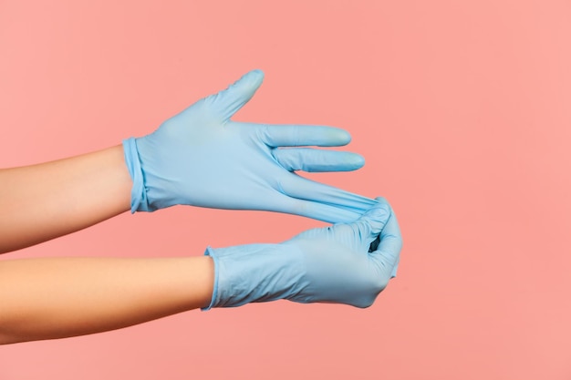 Profile side view closeup of human hand in blue surgical gloves
showing how to take of gloves.