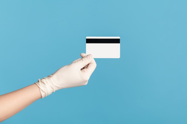 Profile side view closeup of human hand in white surgical gloves holding classic credit card.