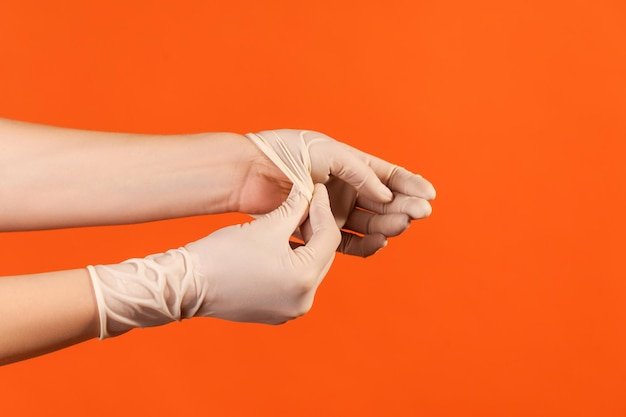 Profile side view closeup of human hand in white surgical gloves showing how to take of gloves.