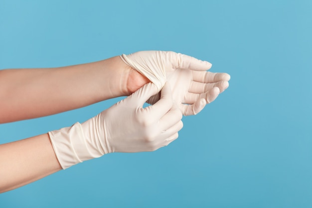 Profile side view closeup of human hand in white surgical\
gloves showing how to take of gloves.