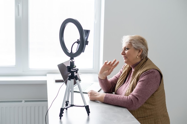 Profile side view portrait of her she nice attractive addicted focused gray-haired blonde granny playing network web virtual team game at industrial loft modern concrete style interior house flat.