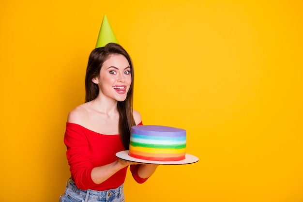 Profile side view portrait of her she nice attractive funny\
hungry cheerful girl holding in hands yummy tasty cake licking lip\
copy space isolated bright vivid shine vibrant yellow color\
background