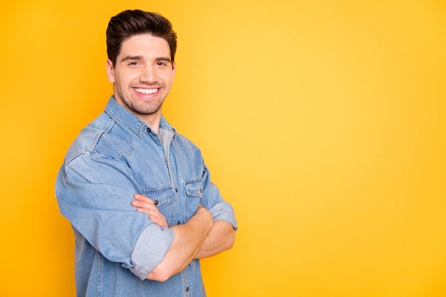 Profile side view portrait of his he nice attractive content cheerful cheery guy folded arms copy empty black place space isolated over bright vivid shine vibrant yellow color wall