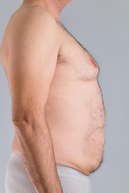 Profile view of the hairy belly of a caucasian man vertical photo isolated on gray background