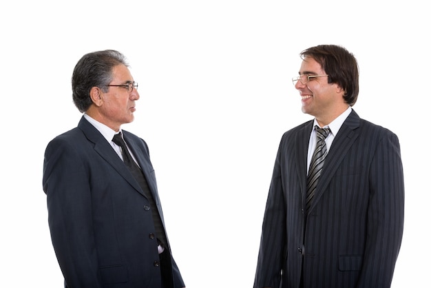 Profile view of happy young and senior Persian businessman smiling and looking each one