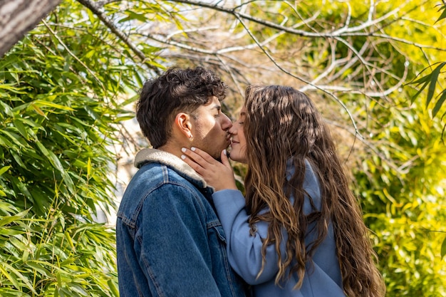 Profile view of an interracial couple kissing in nature