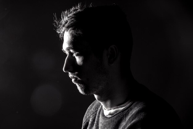 Photo profile view of man with stubble over black background