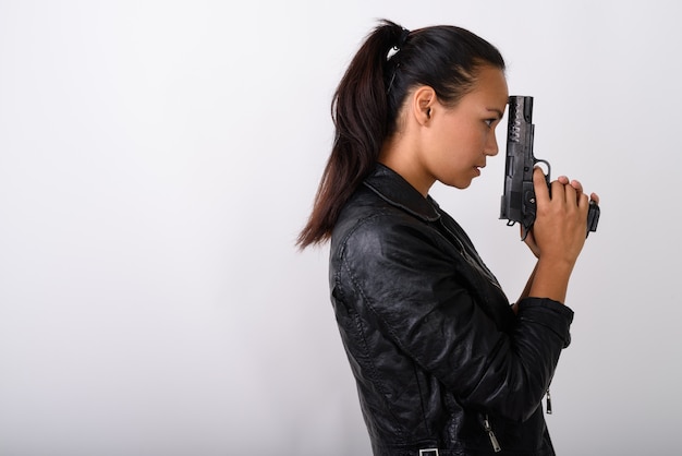 Profile view of young Asian woman holding handgun against white space