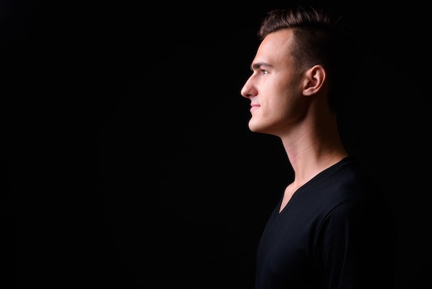 Photo profile view of young handsome man against black background